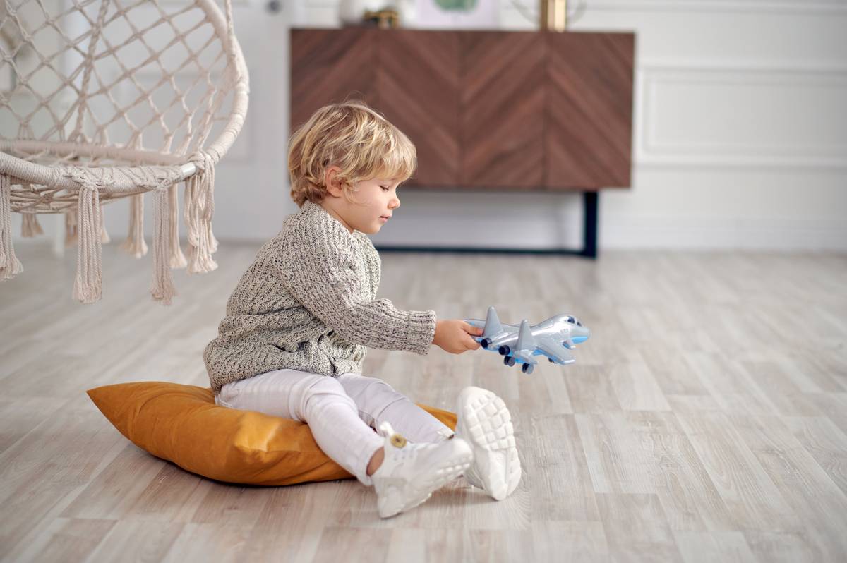 A child sitting upright in a kids gaming floor chair with proper back support while playing on a console